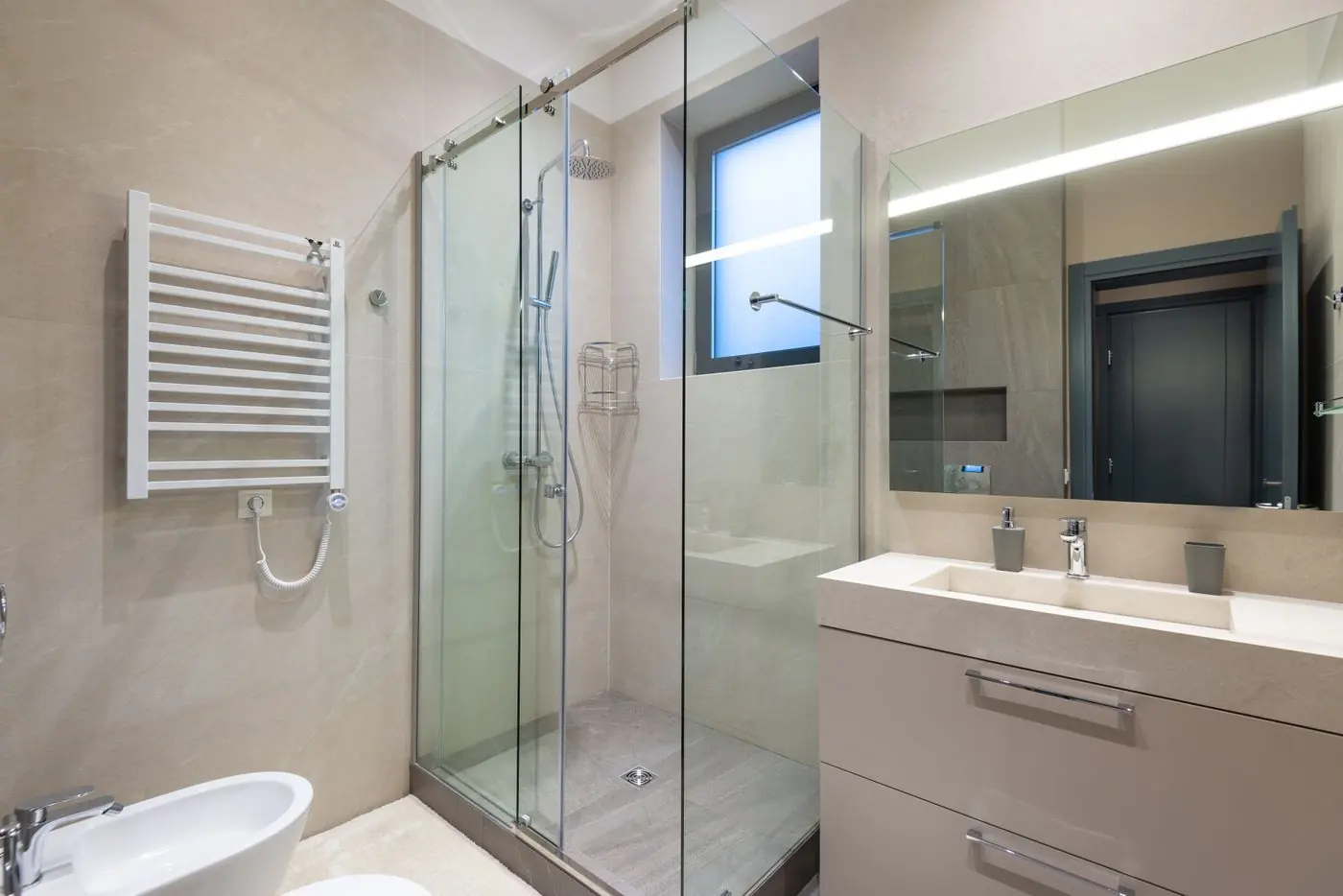Badkamer met glazen douche en handdoekradiator in lichte tinten